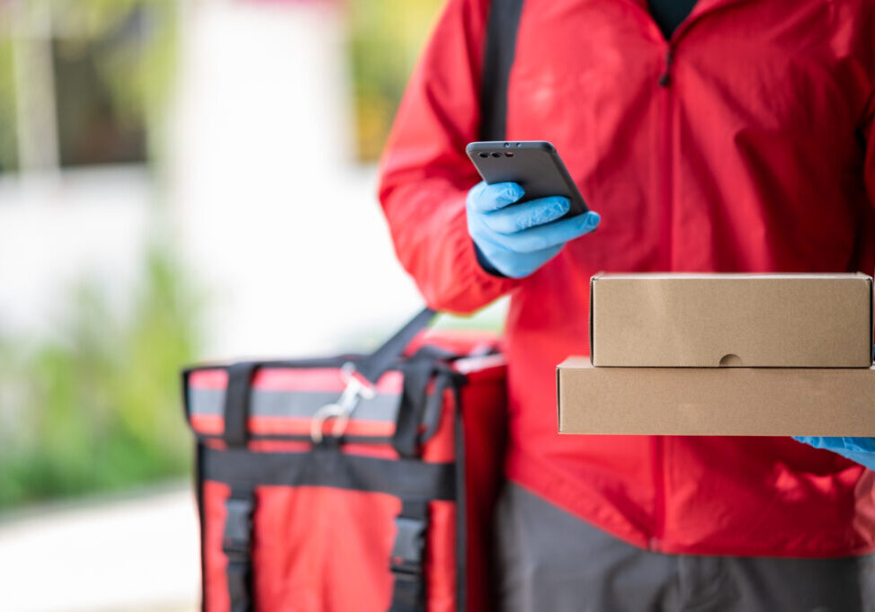 Close up delivery man Wearing blue gloves in red cloth Searching for customer address by mobile phone